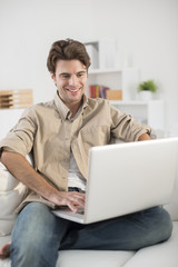 man sitting in couch using laptop computer