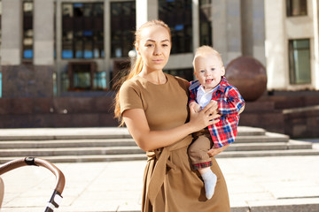 Fashionable modern mother on a urban street with a pram. Young m