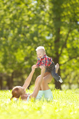 Cute little baby in the park with mother on the grass. Sweet bab