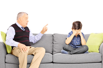 Angry grandad shouting at his nephew, seated on a sofa