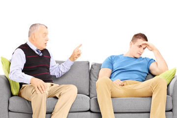 Father reprimending his son seated on a modern sofa