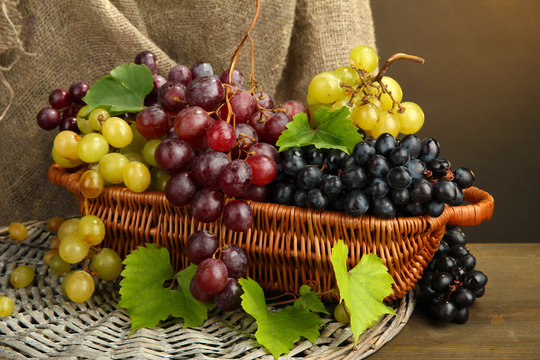 assortment of ripe sweet grapes in basket, on burlap background