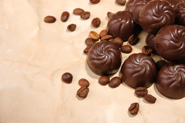 Chocolate candies and coffee beans, on beige paper background