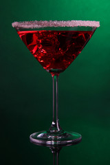 Red cocktail in martini glass on dark green background