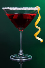 Red cocktail in martini glass on dark green background