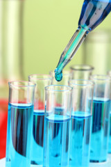 Laboratory pipette with drop of color liquid over glass test