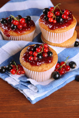 Tasty muffins with berries on wooden table