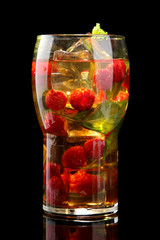 Iced tea with raspberries and mint on black background