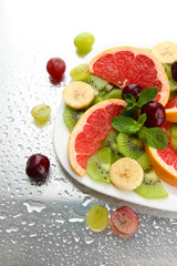 Assortment of sliced fruits on plate with drops