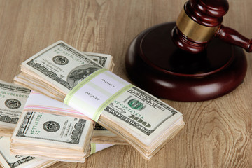 Stacks of money and judges gavel on wooden table