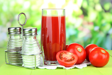 Tomato juice in glass, on wooden  table, on bright background