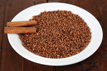 Buckwheat groats in plate on wooden background