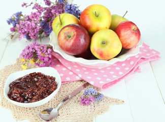 Juicy apples on plate on white wooden table