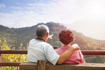 senior couple sitting on the bench looking the nature view