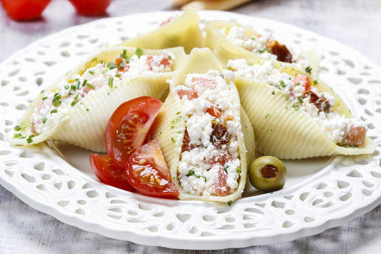 Italian cuisine: stuffed pasta shells on white plate.