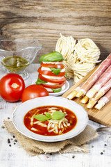 Italian cuisine: tomato soup, breadsticks with ham, caprese sala