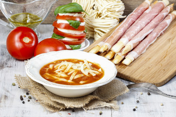 Italian cuisine: tomato soup, breadsticks with ham, caprese sala