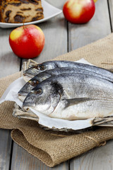 Gilt-head bream fishes in wicker basket on wooden table.