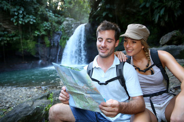 Hikers looking at map by waterfall