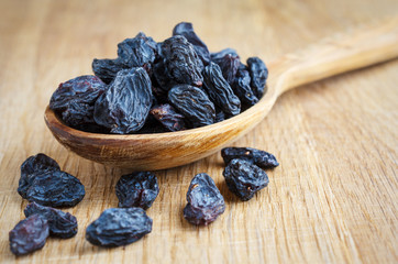 Wooden spoon with raisins on a wooden surface