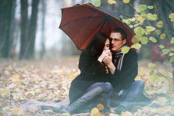 Lovers man and woman under an umbrella in the autumn forest