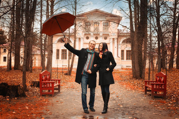 Lovers man and woman under an umbrella in the autumn forest