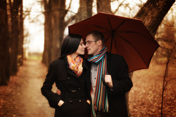 Lovers man and woman under an umbrella in the autumn forest