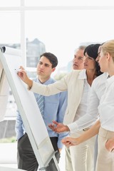 Interested colleagues watching businesswoman writing on whiteboa