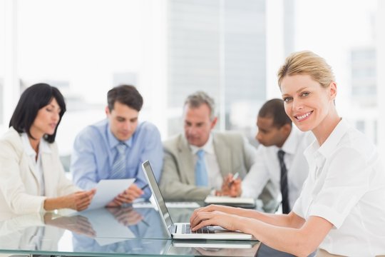 Businesswoman using her laptop during a meeting smiling at camer
