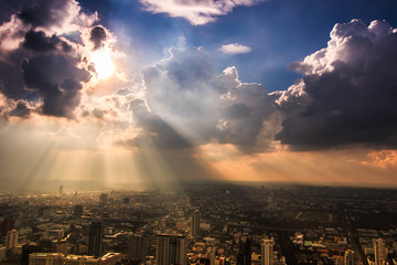 Fototapeta premium Rays of light shining through dark clouds in Bangkok, Thailand