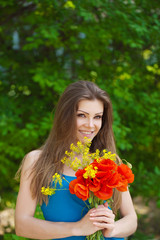 Naklejka premium Portrait of a cheerful woman outdoors with red poppy flowers