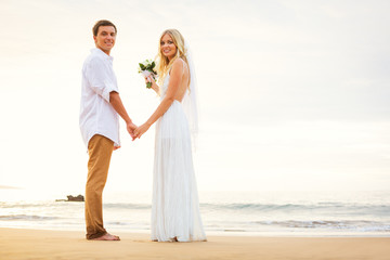 Fototapeta na wymiar Just married couple holding hands on the beach