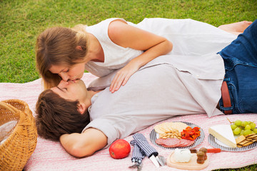 Obraz na płótnie Canvas Attractive couple on romantic afternoon picnic kissing