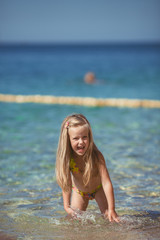 little girl sitting on the beach near the sea