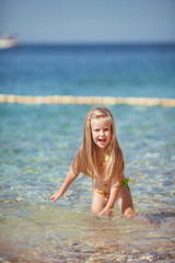 little girl sitting on the beach near the sea