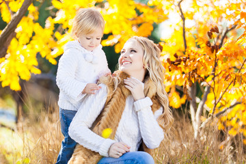 Young mother playing with her daughter in autumn park