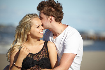 Fototapeta premium Young beautiful couple in love sitting near the water