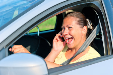 beautiful girl behind the wheel with phone laughing