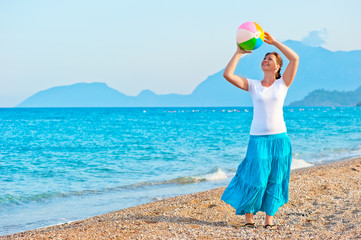 Fototapeta na wymiar girl plays with a beach ball near the sea