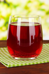 Glass of fresh garnet juice on table on bright background