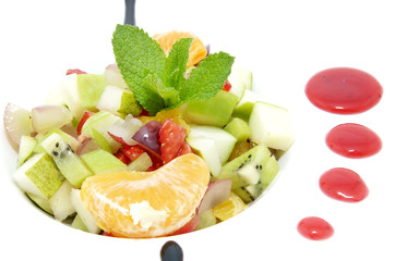 fruit salad decorated with mint on a white plate