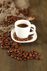 Cup of coffee and coffee beans on wooden background