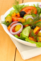 Fresh salad in plate on wooden table