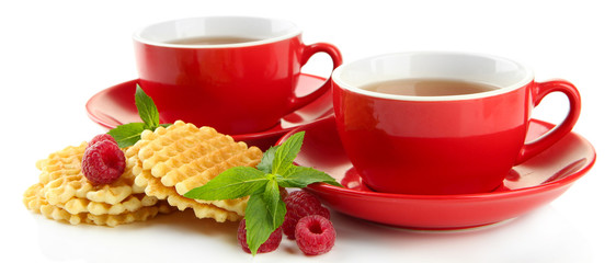 Cups of tea with cookies and raspberries isolated on white
