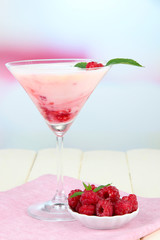Raspberry milk dessert in cocktail glass, on light background