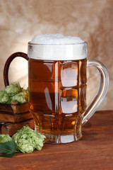 Glass of beer and hops, on wooden table