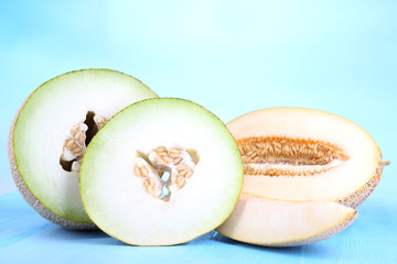 Ripe melons on wooden table on blue background
