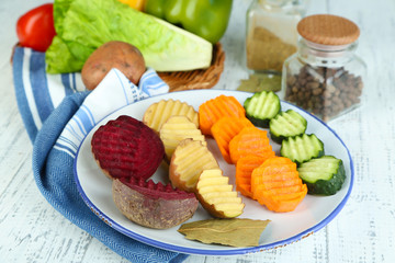 Beautiful sliced vegetables, on plate, on wooden background