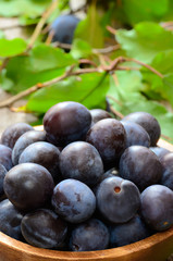Plums in bowl on the wooden table