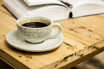 Cup of coffee and opened book with pen on wood table